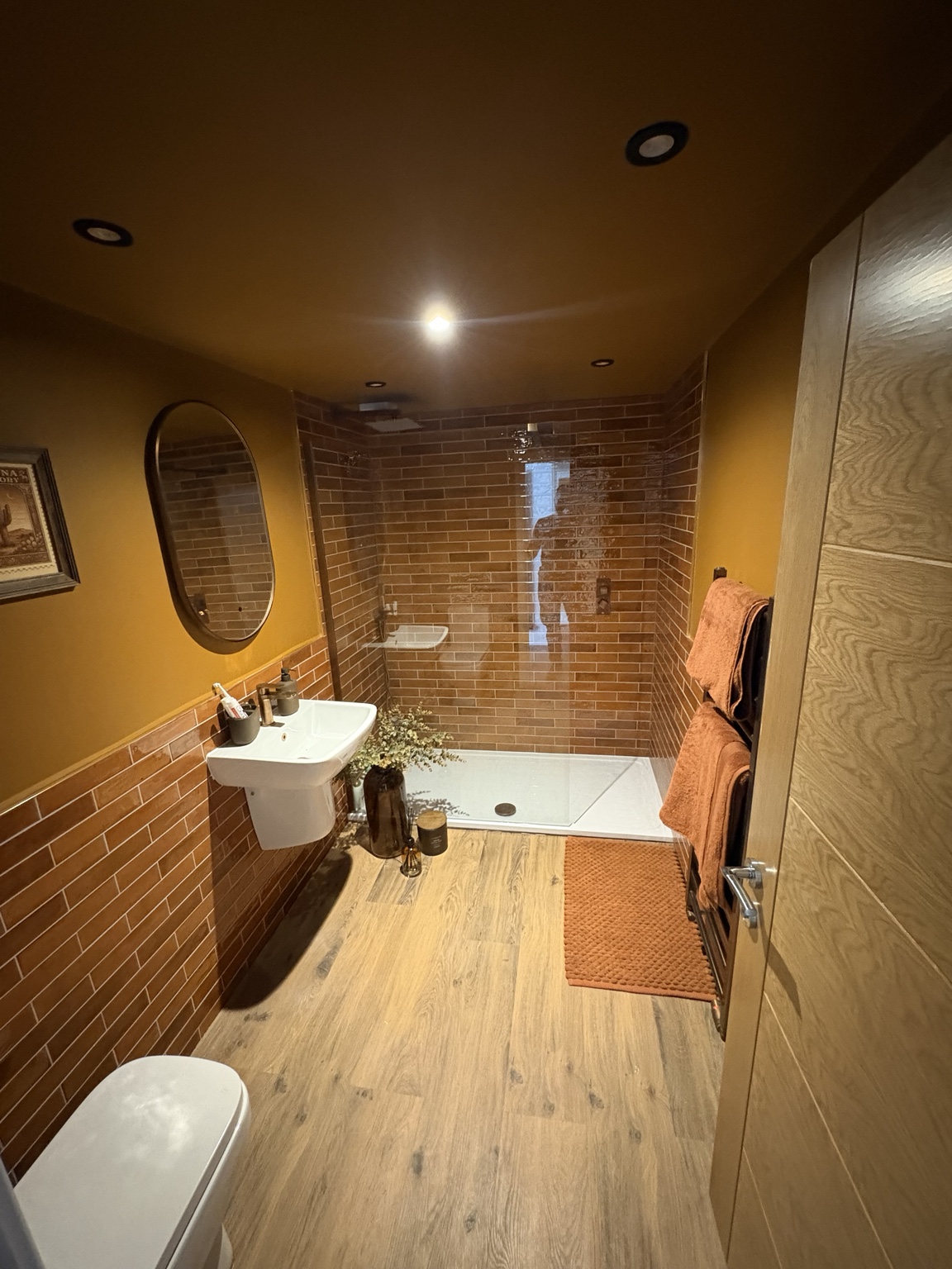 Warm-toned bathroom with brick-effect wall tiling by JMB Plumbing & Heating