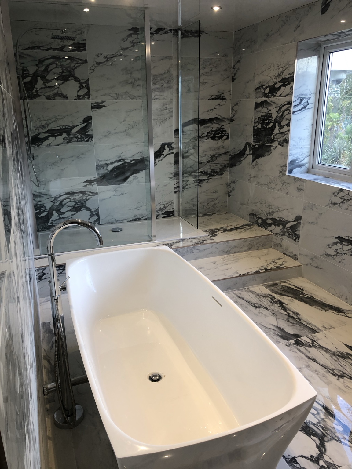 Marble-effect bathroom with freestanding bath and shower