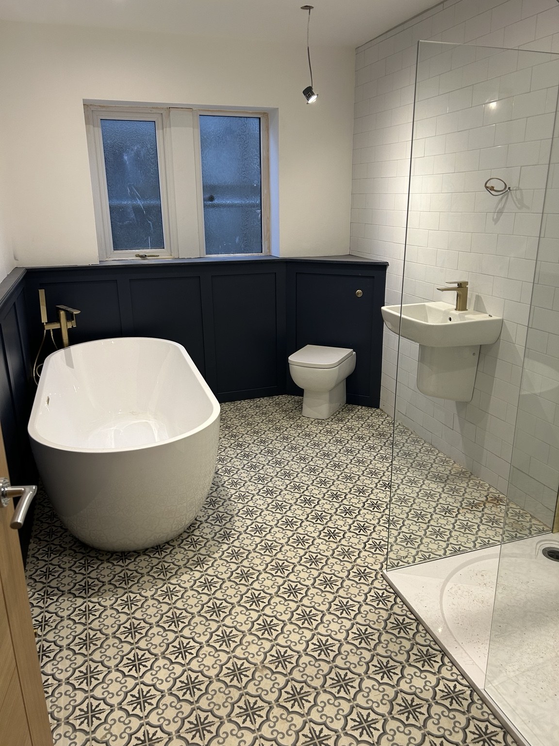 Patterned-floor bathroom with freestanding bath by JMB Plumbing & Heating